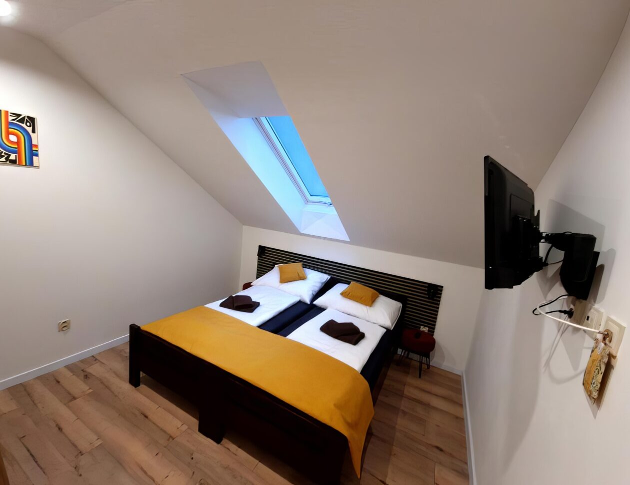 Standard room interior with TV, double bed and roof window